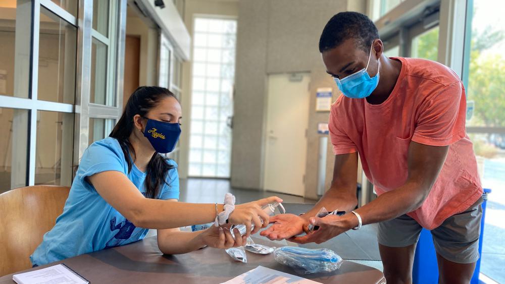 Woman gives man hand sanitizer