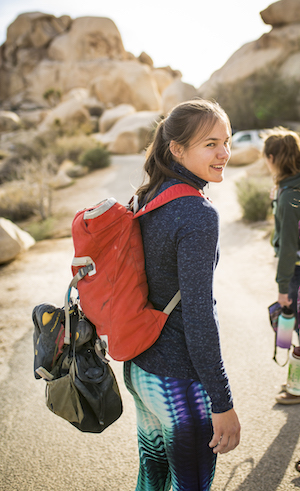 Ula is hiking in a desert area with a backpack and is turning around. 