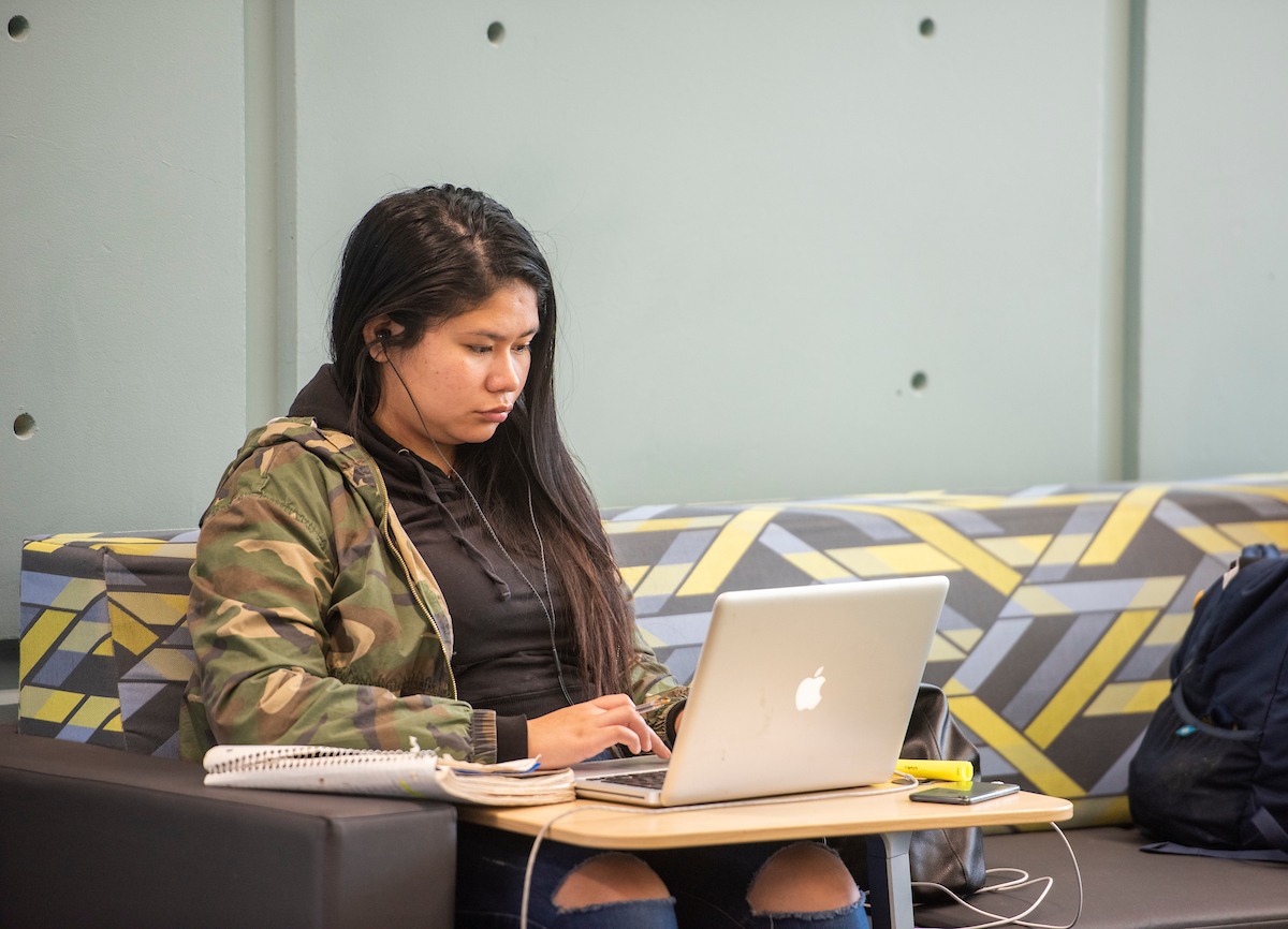 A student studies on a brightly patterned couch. 