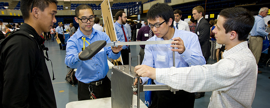 3 students demonstrate their invention to an onlooker