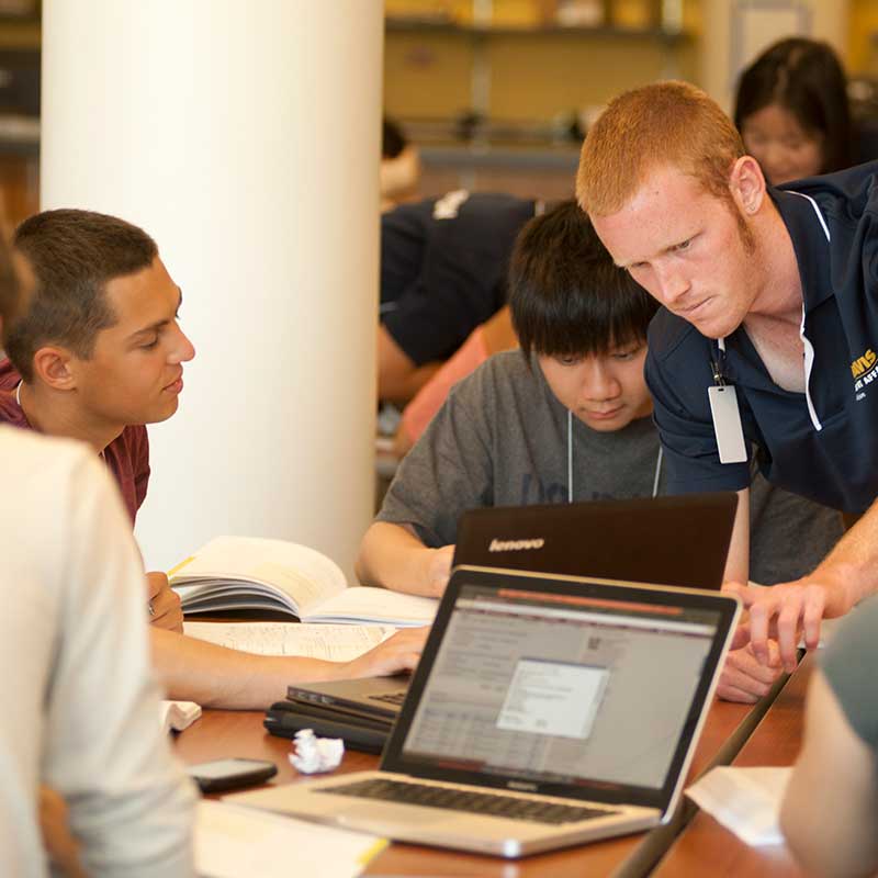 Male student directing other students grouped around a table