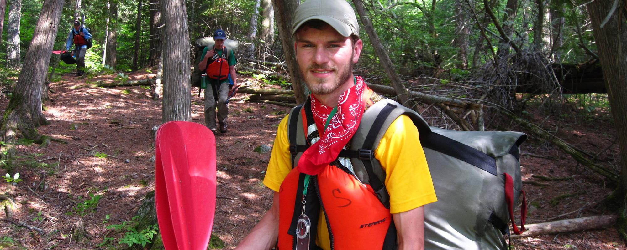 Man standing in forest with a kayak paddle