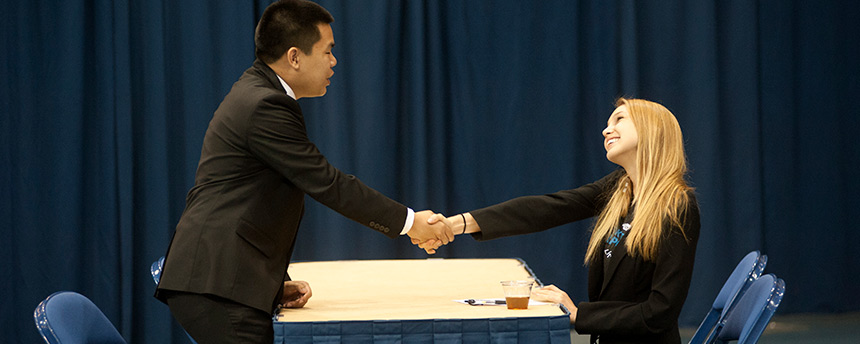 A male, left, shakes hand with a female, both in business attire