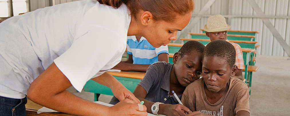 Adult woman leaning over to teach two young boys