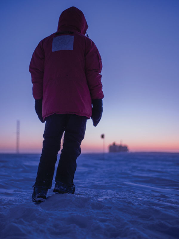 A man stands in the snow at dawn