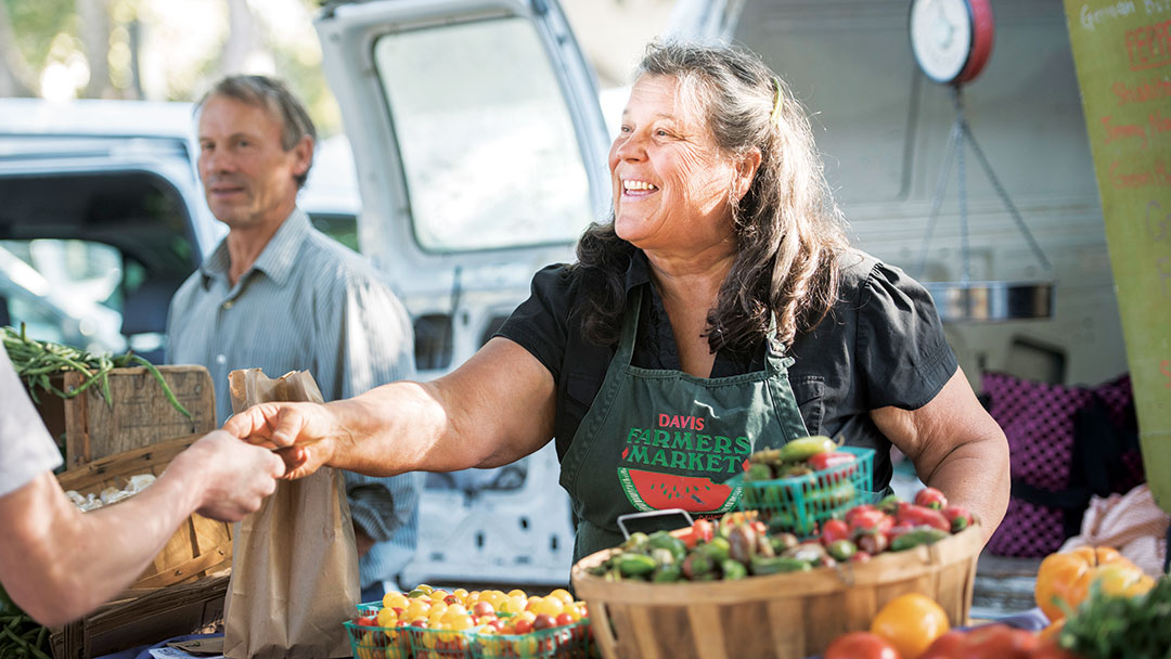 A woman vendor greets customers at the farmer's market