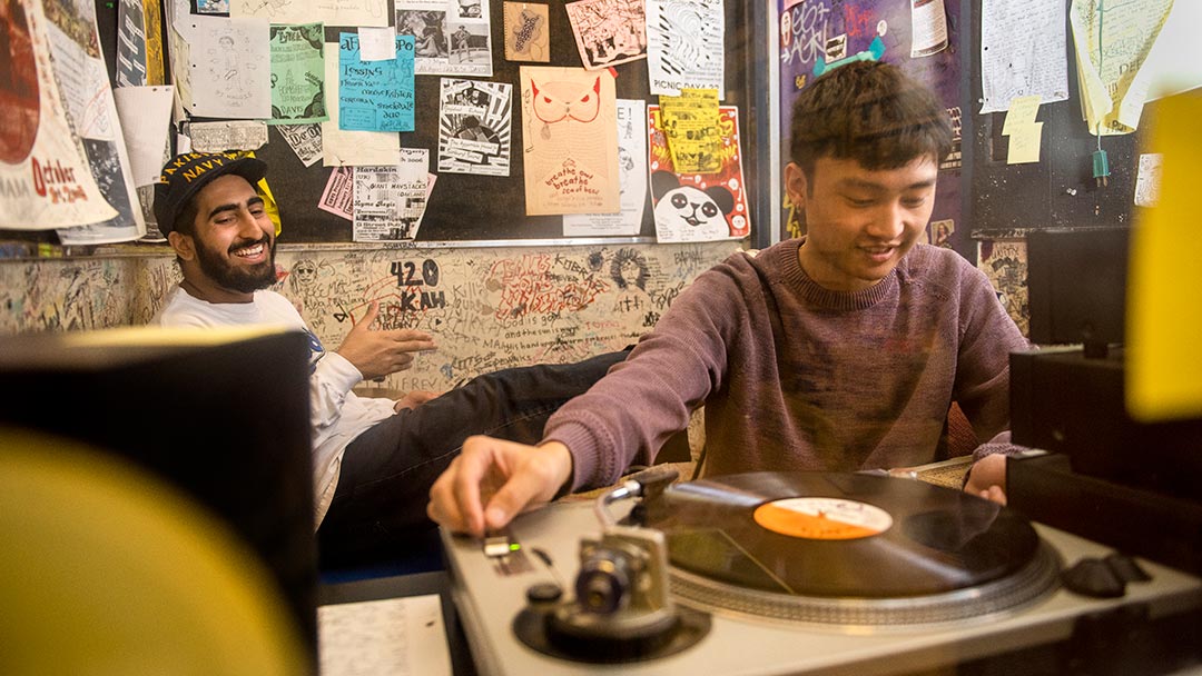 Two male students in a listening room with a turntable