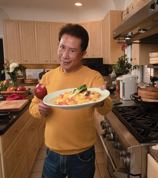 Chef Martin Yan holds plate of food