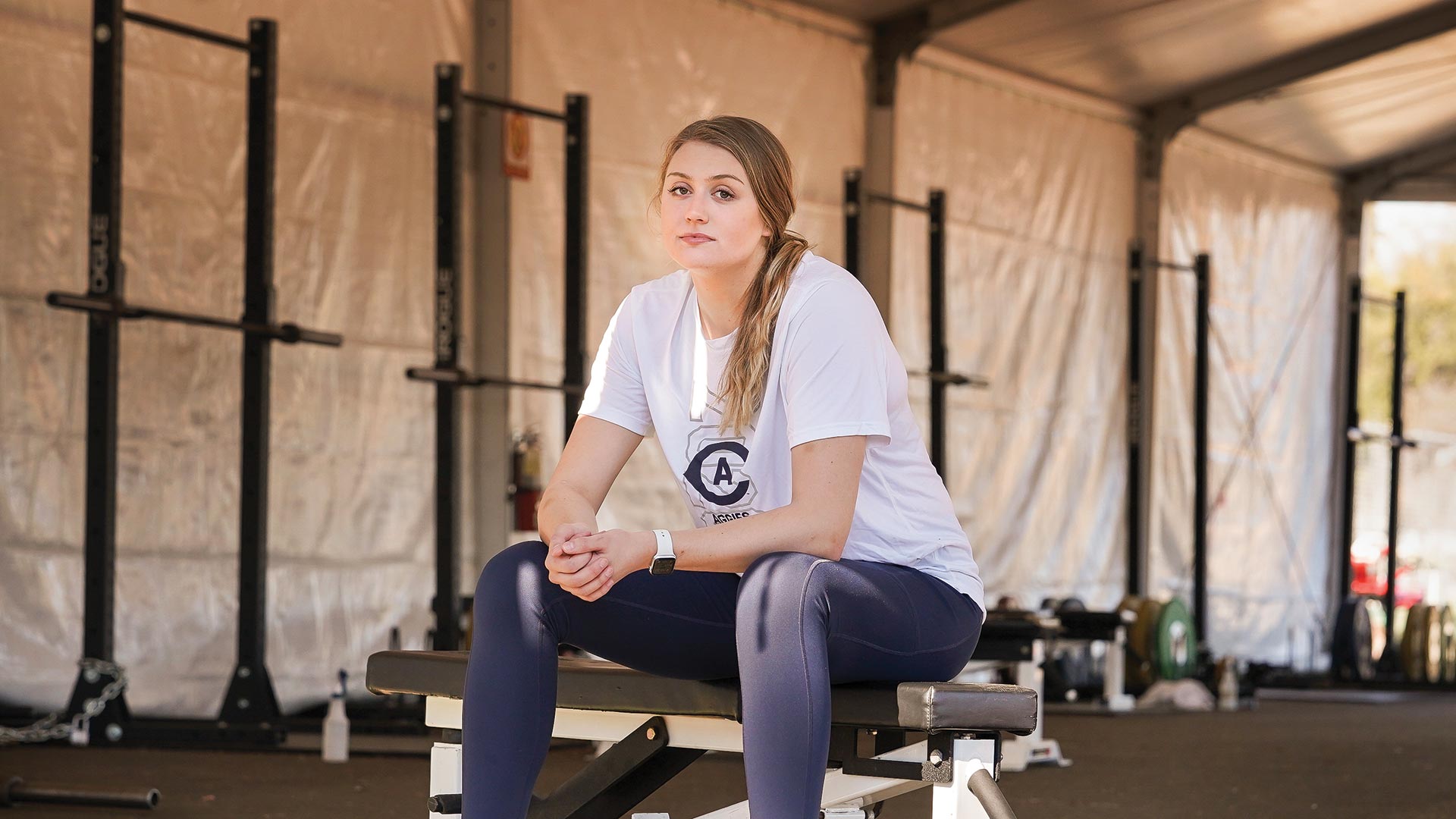 A student sits on a weight bench in a tent