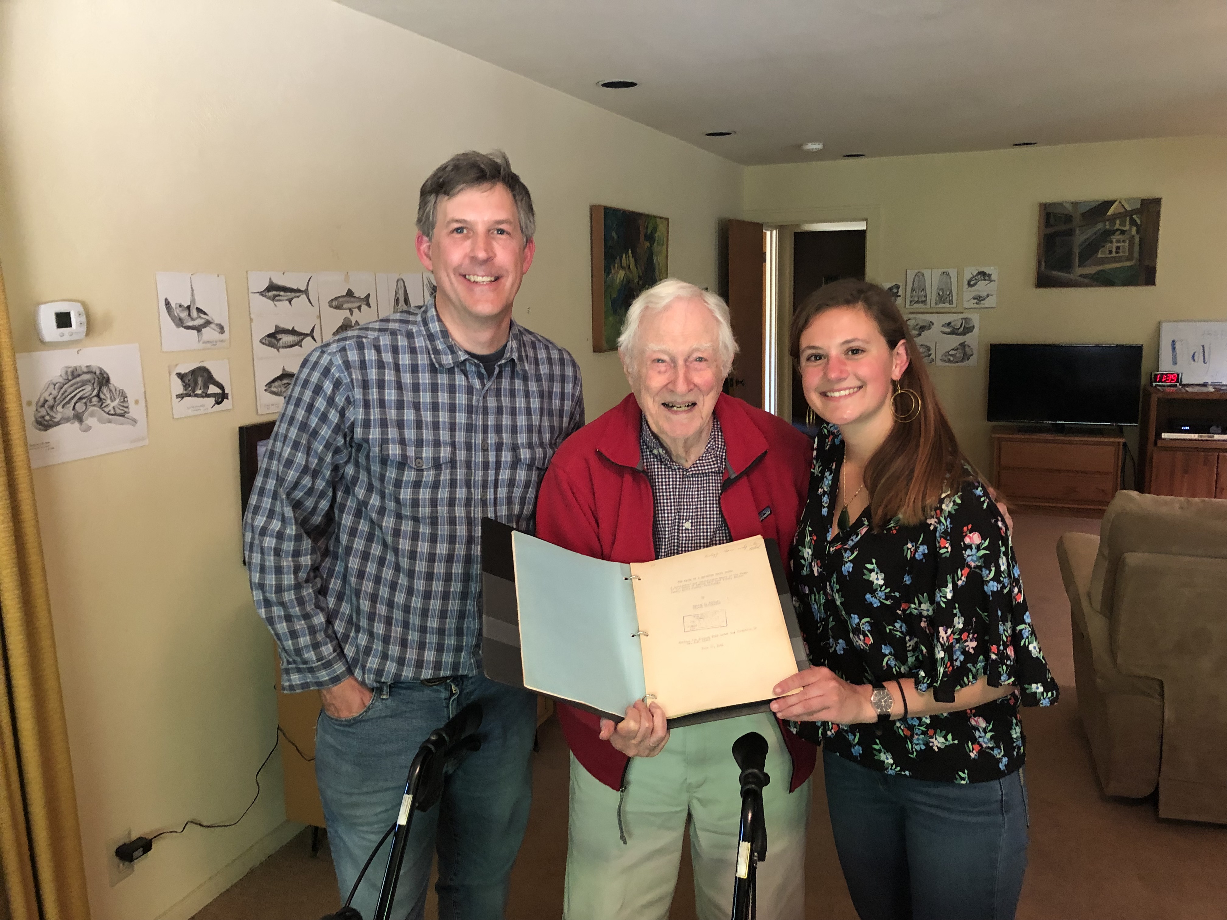 Eric Sanford, Milton Hildebrande and Emily Longman smile at camera holding 1941 mussel bed manuscript