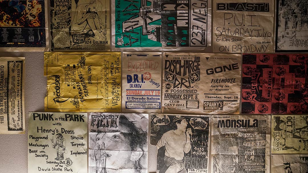 Photo of a portion of a wall that has been covered completely with flyers and posters for concerts. Most are handwritten or photocopied, and have an indie-produced feel.