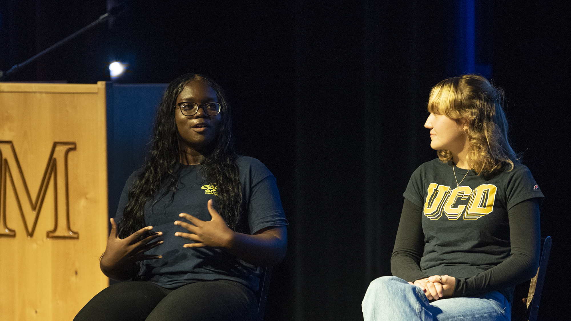 Two seated women, one talking and one listening