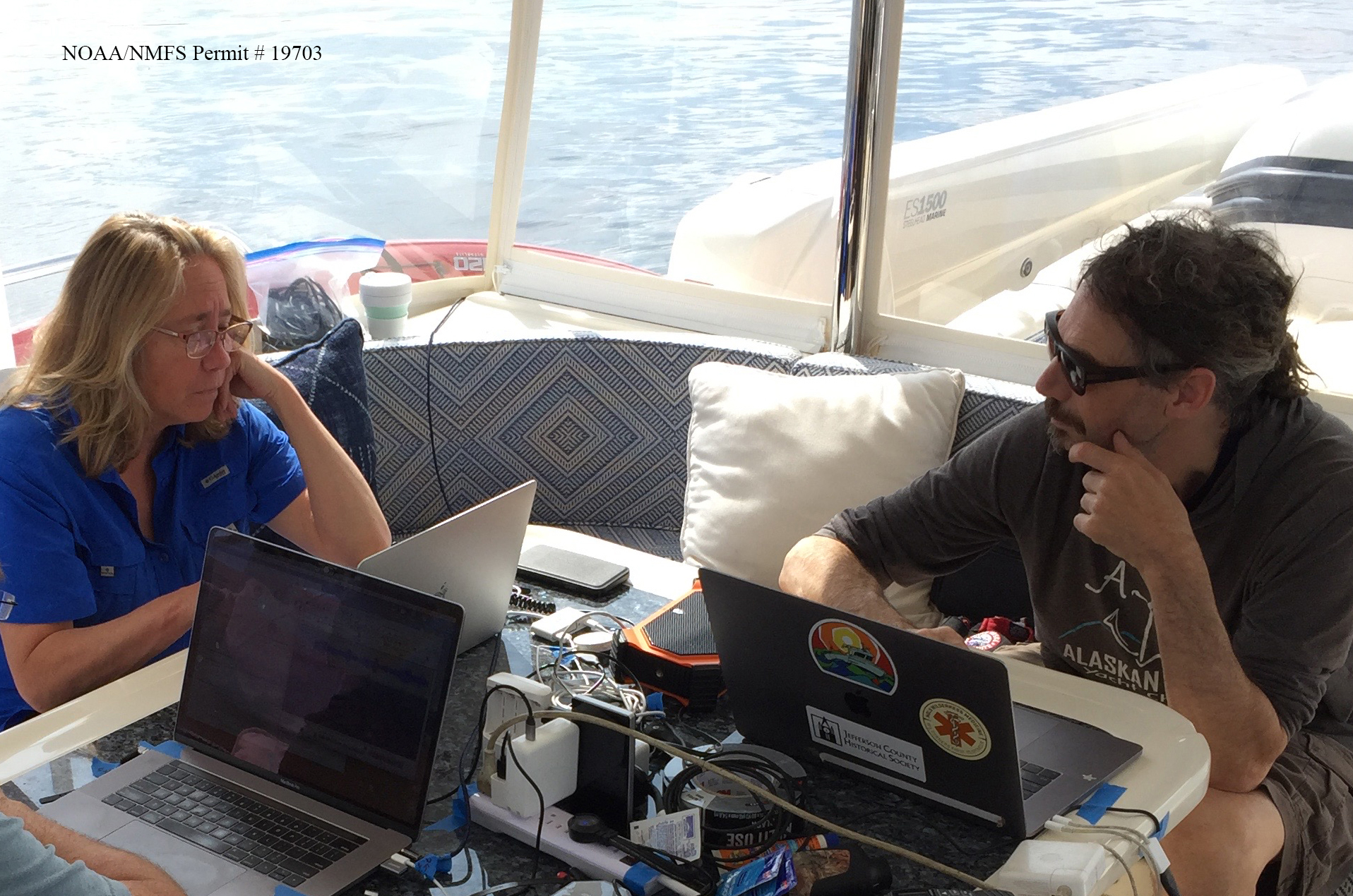 Brenda McCowan and Fred Sharpe work in front of computers on their research vessel. They are hoping that communication with humpback whales will help them detect and interpret signals from outer space. (Jodi Frediani)