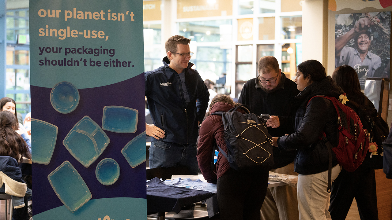 Around a table, students sign up for the app used to scan used containers. 
