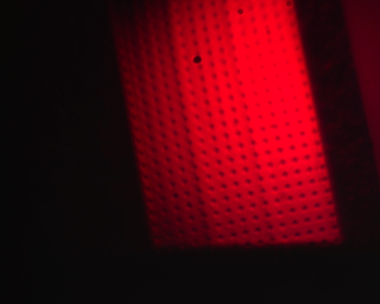 Red backlit infrared sensor with perforated panel and grid of small black holes