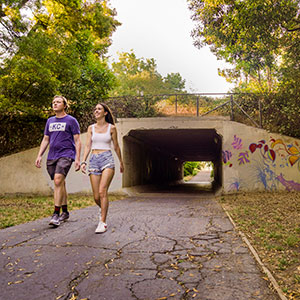 A male and female student are walking on a bike path