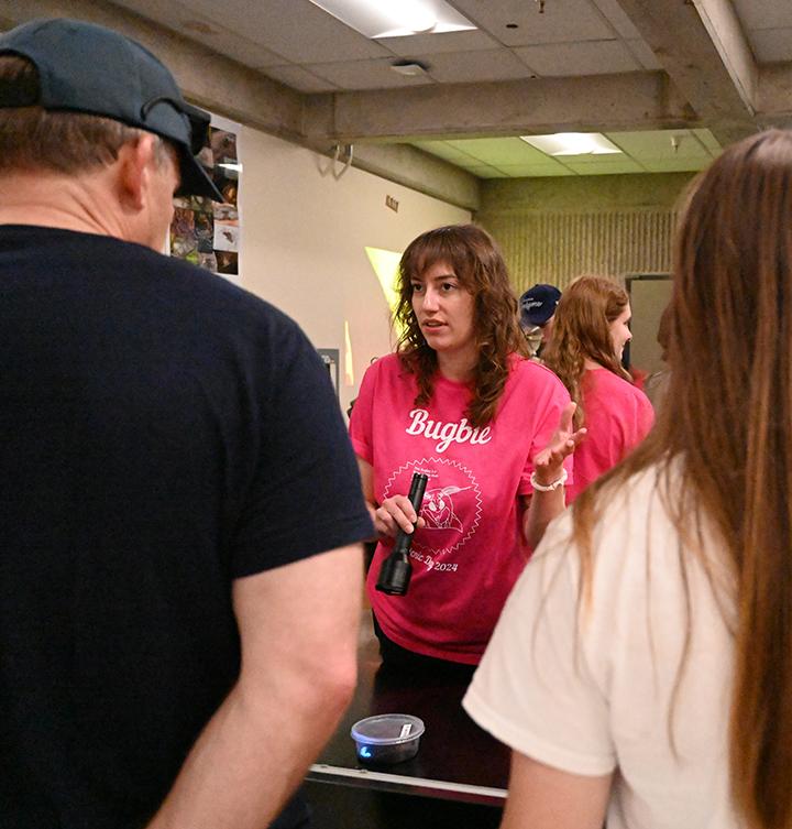 Person in pink T-shirt talks to visitors