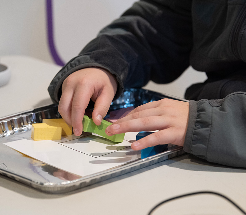 Child's hands while solving a puzzle at a table.