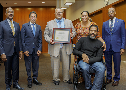 Three university officials pose with four members of Abiel Malepeai's family