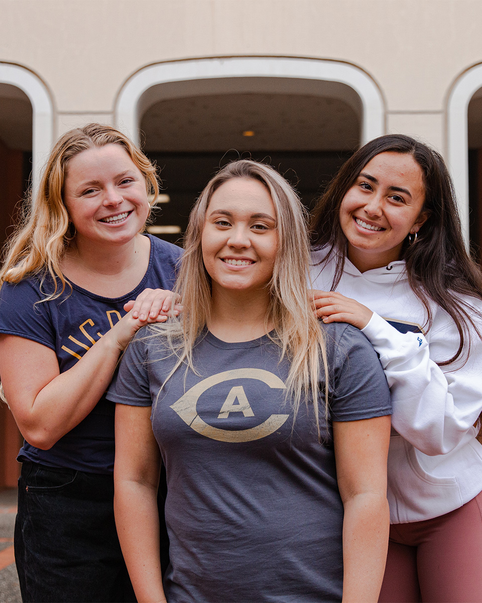 Three women pose for photo on Mrak Hall stairs.