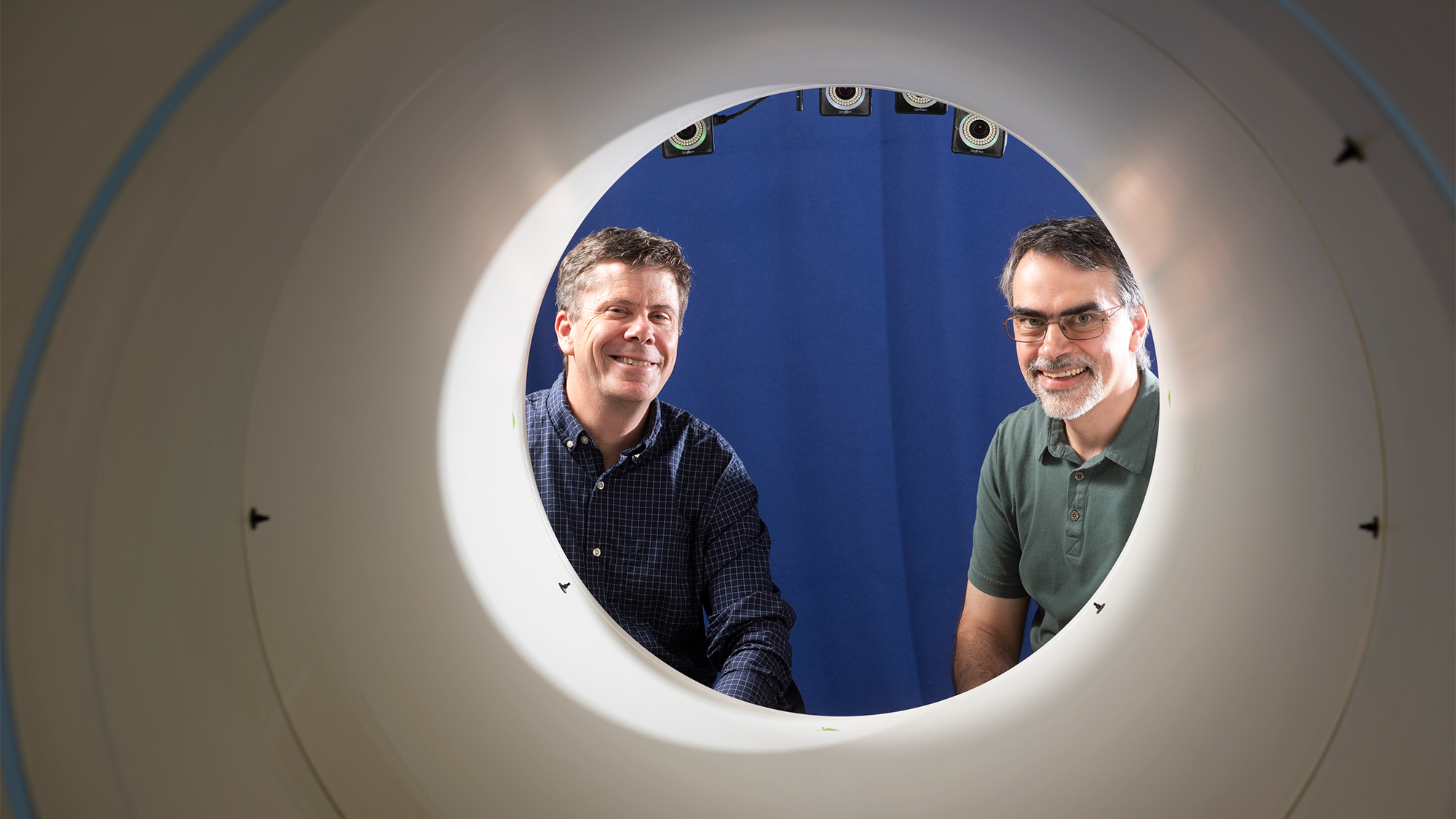 Two researchers posing in a PET Scan machine