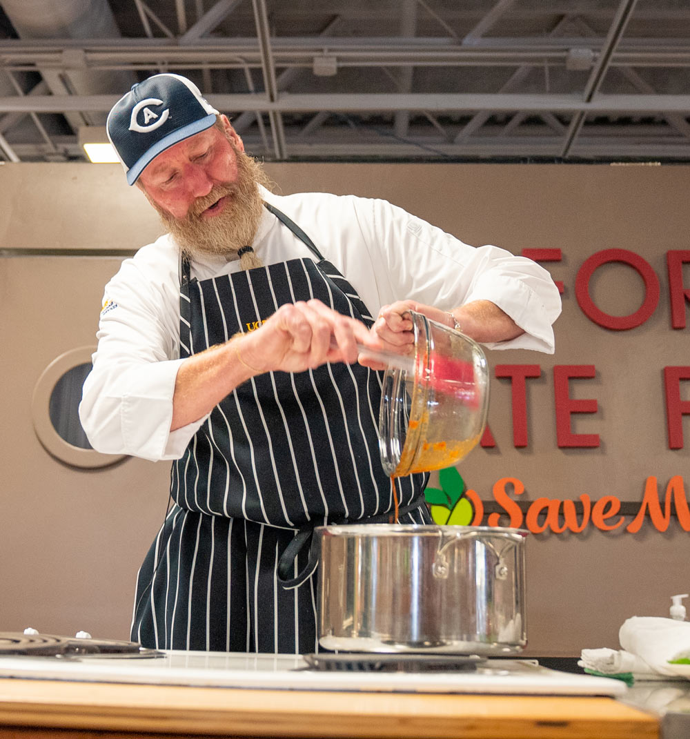 Chef pours ingredients from bowl into pot