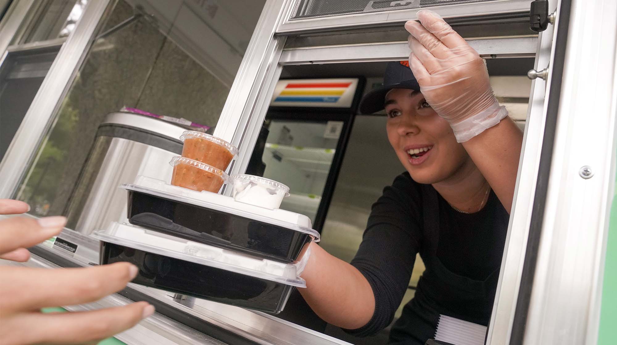 Worker passes out food from AggieEats food truck.