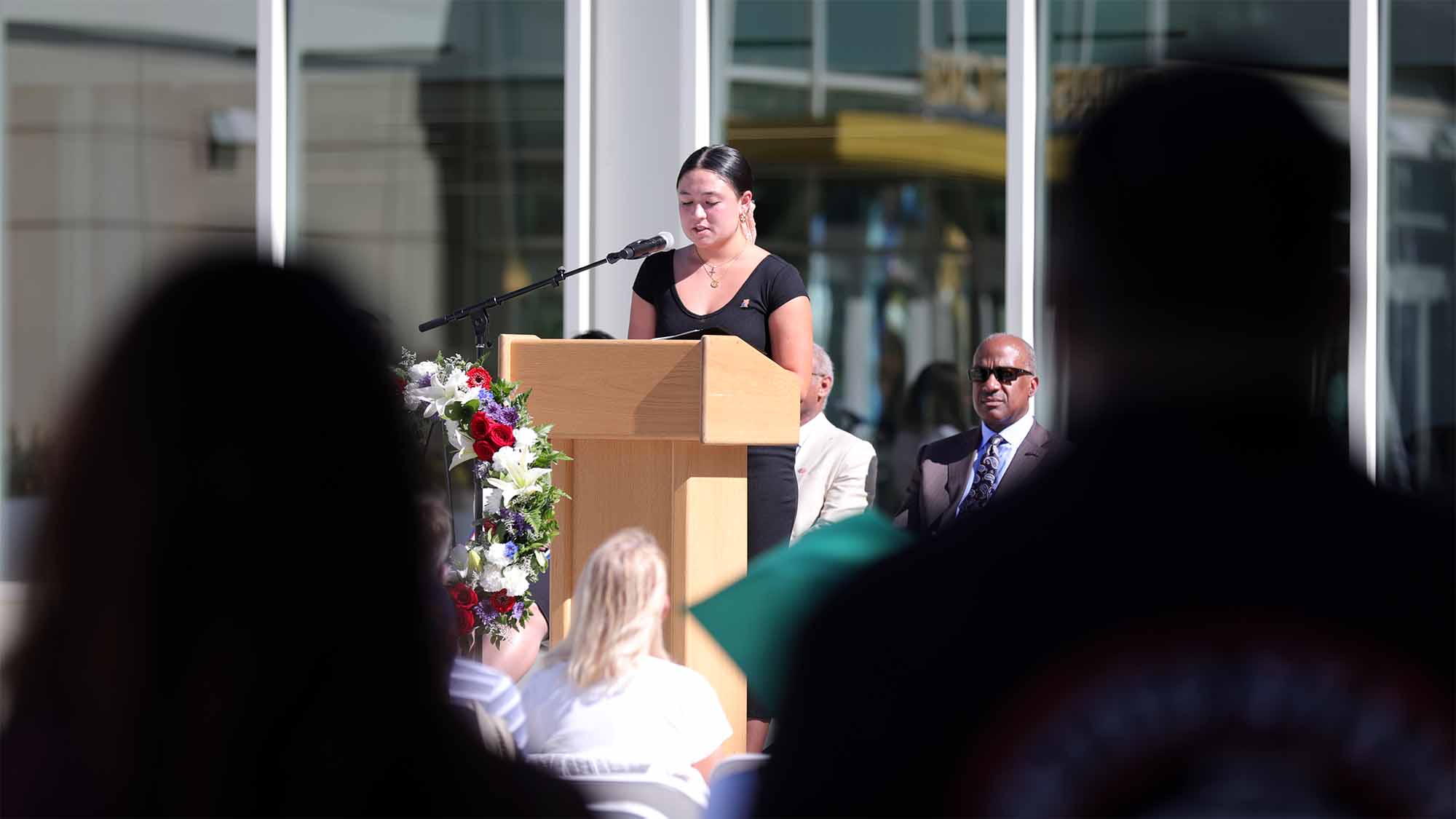 Student reading names on stage at Memorial Day Ceremony.