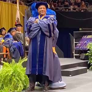 Chancellor Gary S. May poses for photo with Gunrock while both wear commencement regalia