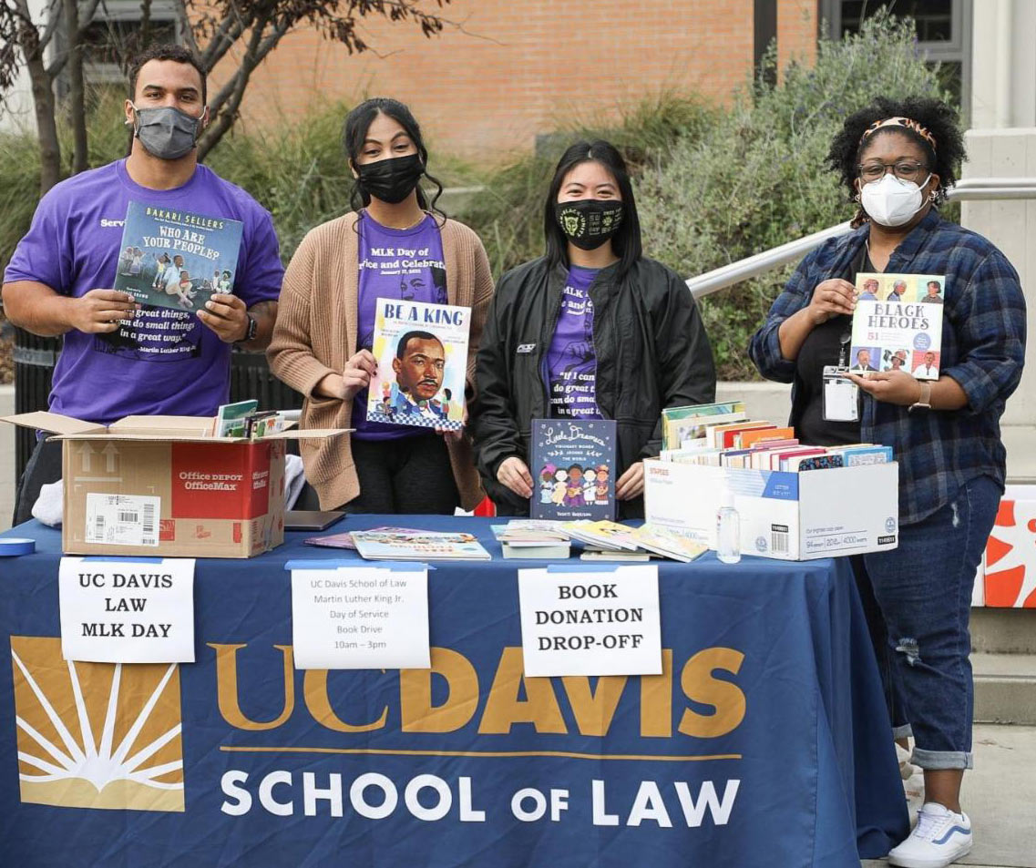 4 people at a table, collecting books at the law school