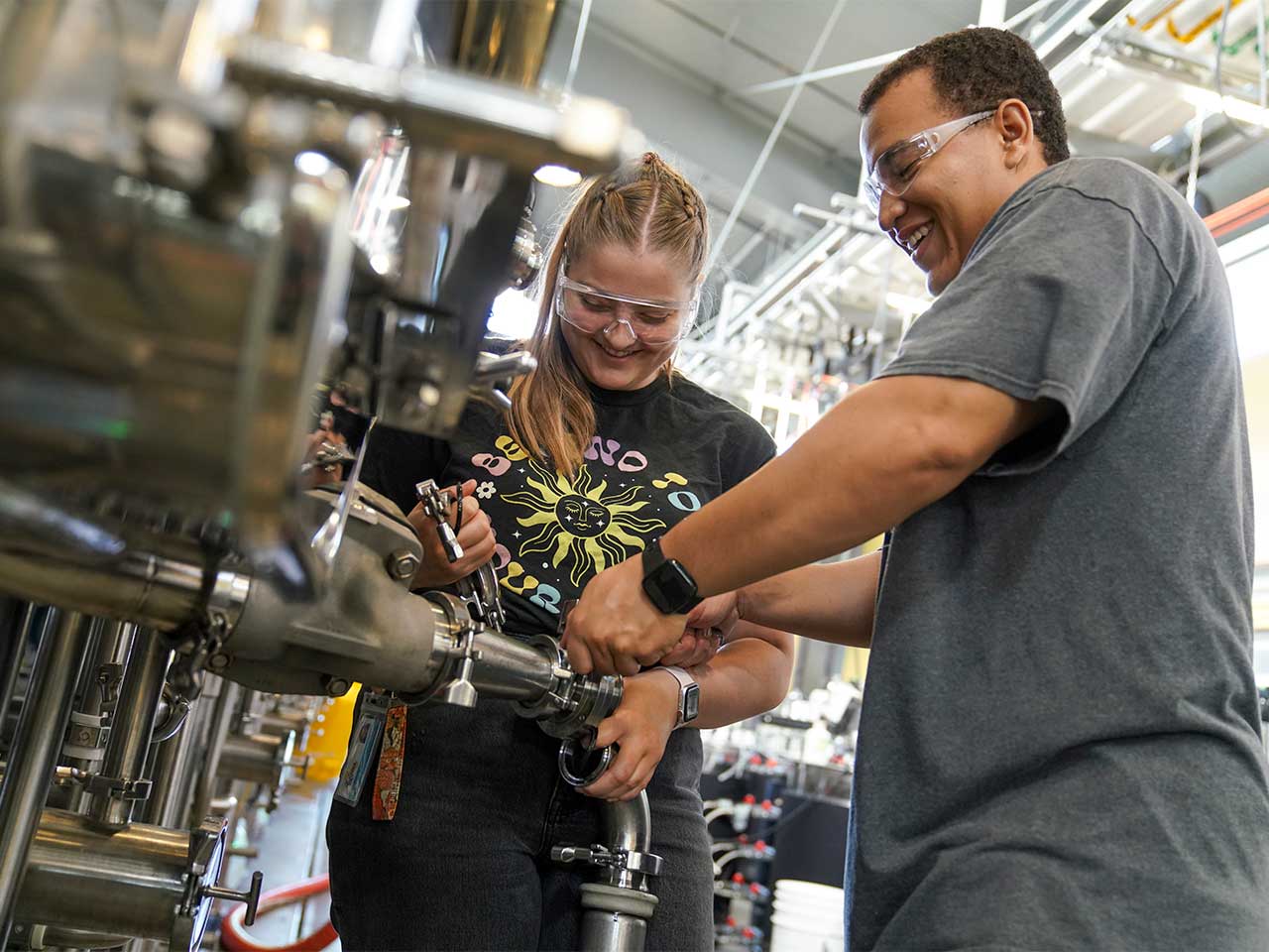 Cameron Rose (female) a senior double majoring in Viticulture and Enology and Managerial Economics and Kyle Williams (male) a senior majoring in Chemical Engineering work together to "rach the lees" in 540 gallon tanks at the winery at the Robert Mondavi Institute for Wine and Food Science.