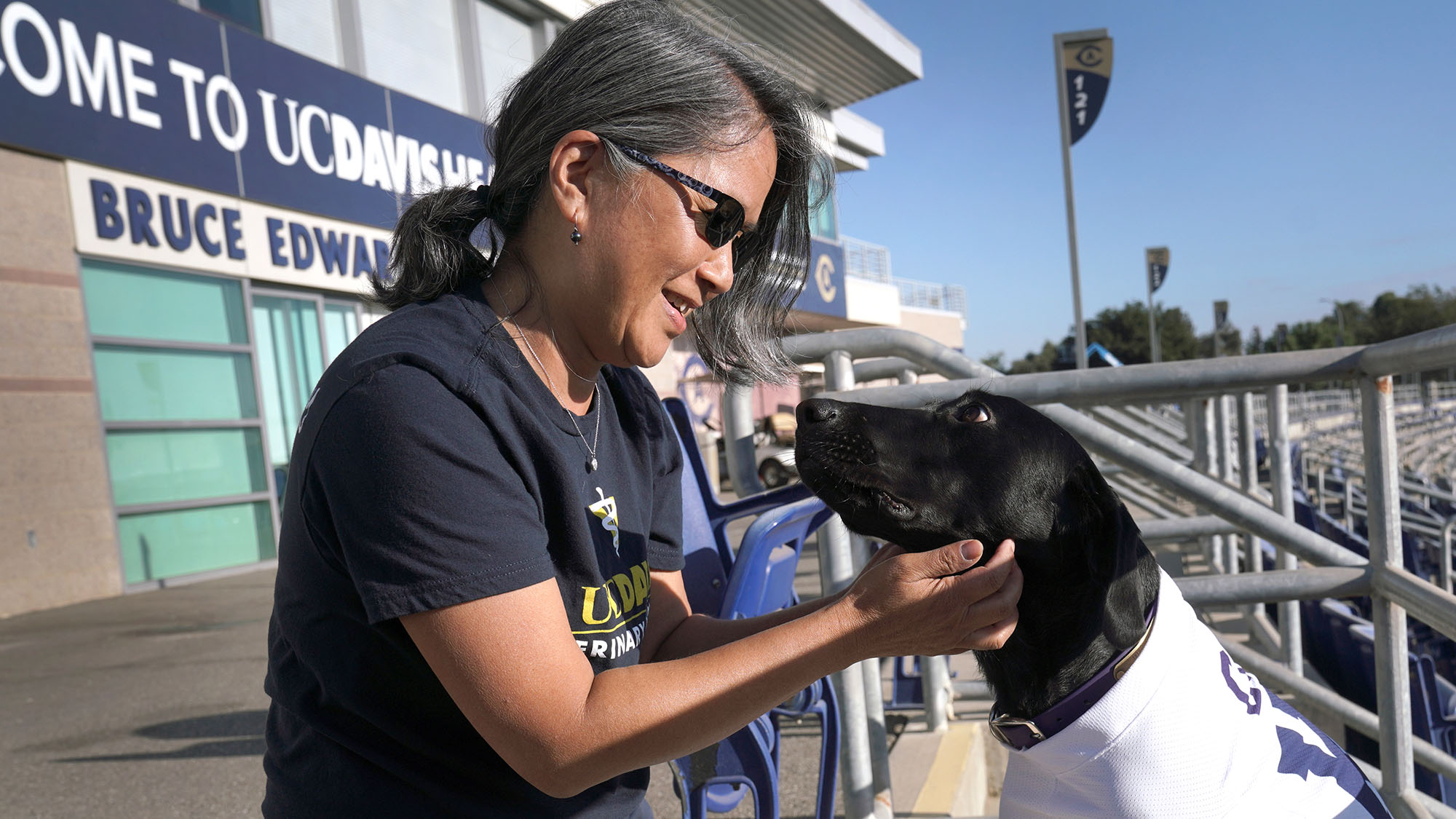 Professor Lisa Tell pets Cori, a black lab