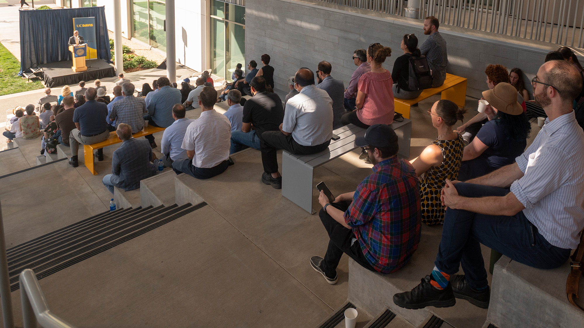 People sitting on stairs listen to Gary S. May speak