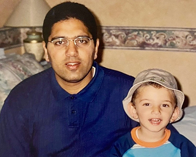 Man and smiling toddler sitting on bed