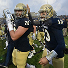 Football players hold the Causeway Classic trophy.