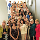 Women pose on a staircase.