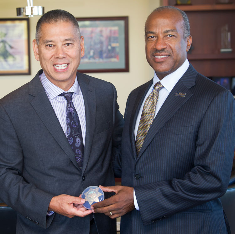 Two men standing together, holding badge