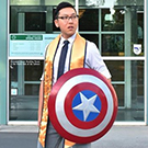 A graduating senior holding Captain America's shield.