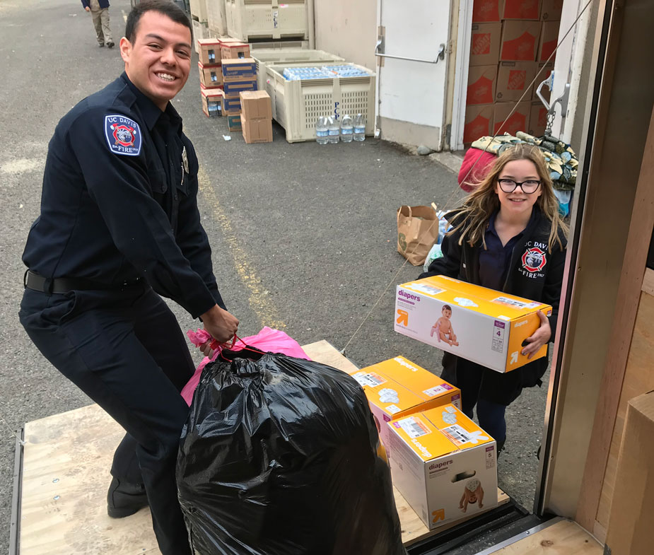 Student firefighter and young girl load trailer.