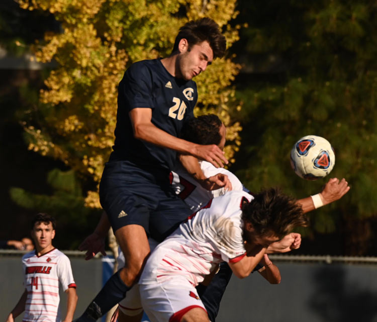 Aggie men's soccer player slides toward the ball.