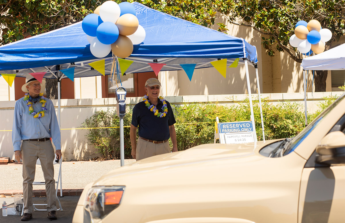 Ken Burtis and Ralph J. Hexter stand under a tent at a goodbye parade for retirees.