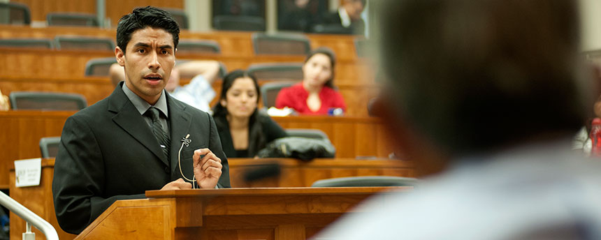 A student stands at a podium in front of a judge