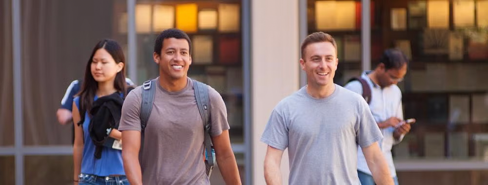 Two students walking out of King Hall and students in the background