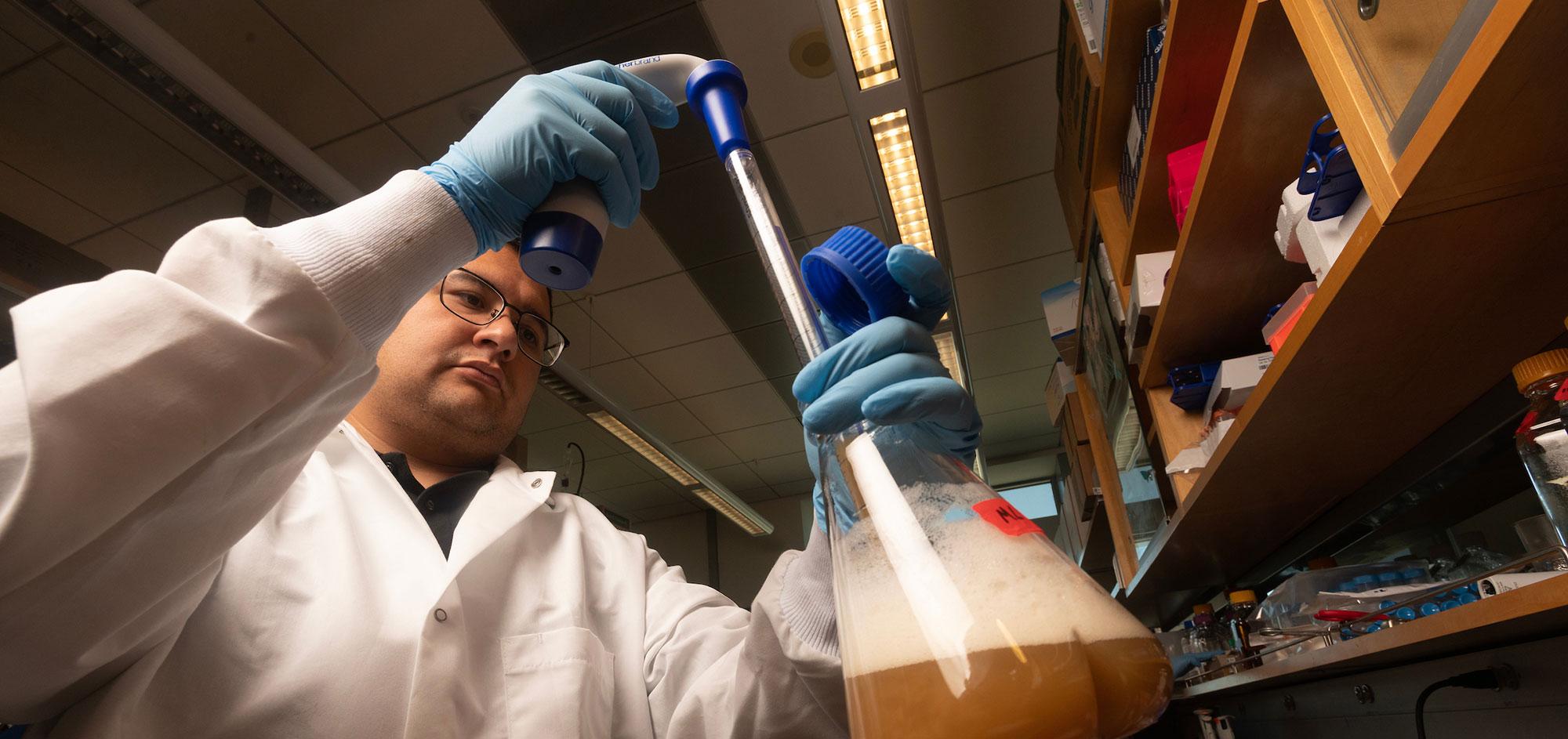 A researcher holds a flask up to the light in his lab