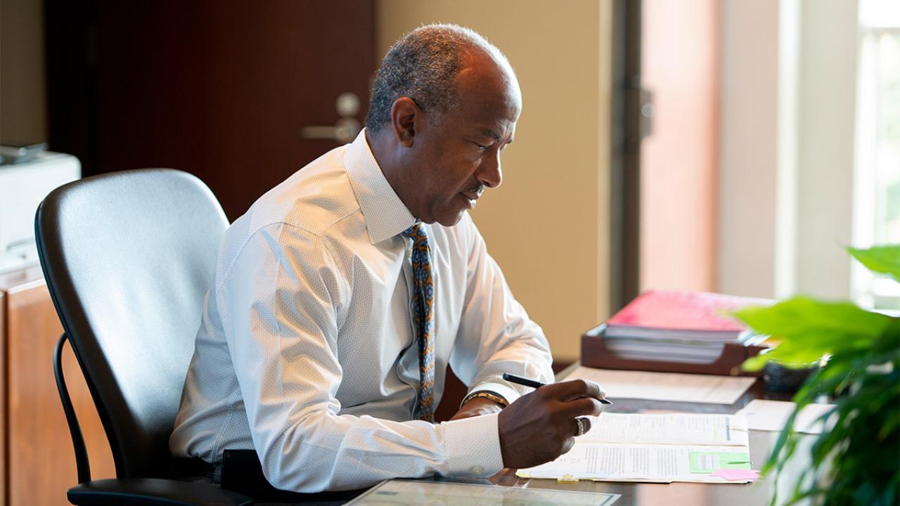 Photo of Gary S. May at desk.