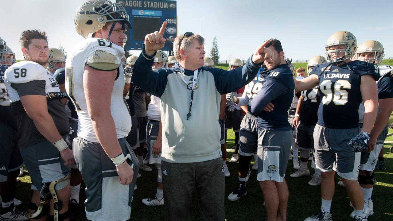 Dan Hawkins speaks to players at a football practice.