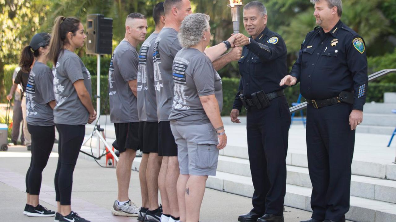 UC Davis Police Chief Joe Farrow and Davis Police Chief Darren Pytel hand off the torch to runners.