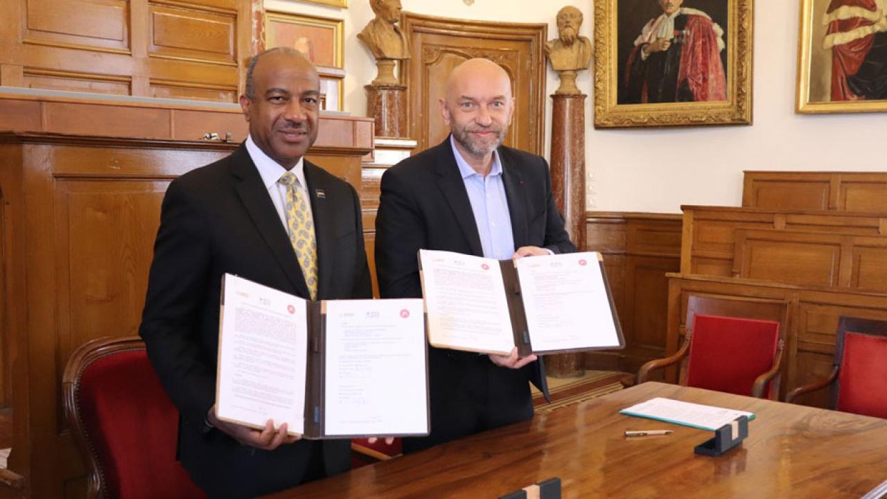 Chancellor May and French official hold up signed doruments in ornate room.