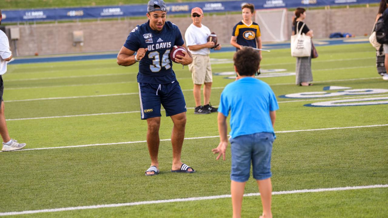 Football player in a drill with a boy.