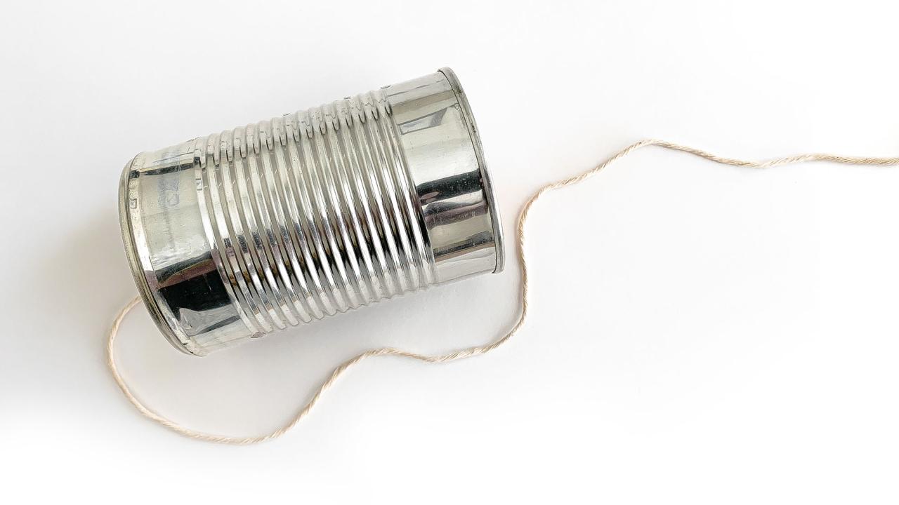 Photo of a tin can laying on its side, with a string coming out of one end.